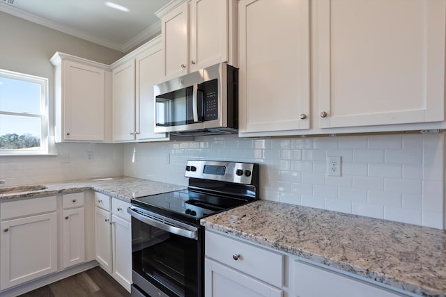 kitchen featuring dark wood finished floors, decorative backsplash, ornamental molding, stainless steel appliances, and white cabinetry