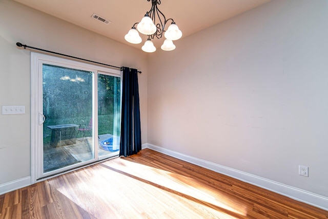 spare room featuring hardwood / wood-style flooring and a chandelier