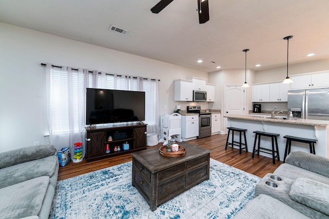 living room with dark hardwood / wood-style flooring, ceiling fan, and sink