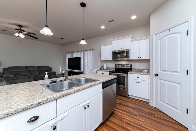 kitchen featuring sink, hanging light fixtures, dark hardwood / wood-style flooring, white cabinetry, and stainless steel appliances