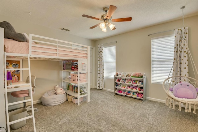 carpeted bedroom featuring visible vents, a textured ceiling, baseboards, and a ceiling fan