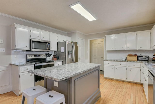 kitchen with white cabinetry, ornamental molding, light wood finished floors, and stainless steel appliances