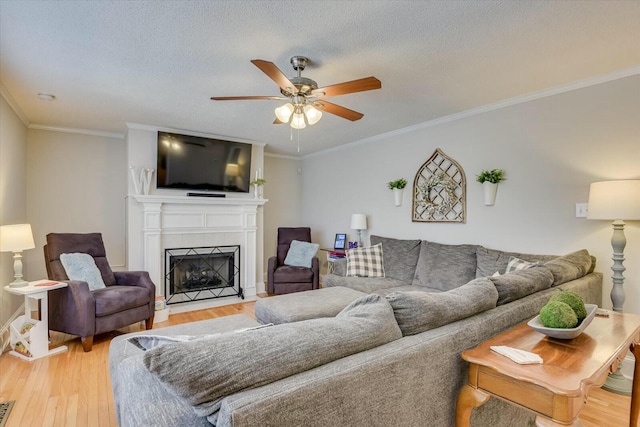 living room with a tile fireplace, a textured ceiling, light wood-type flooring, and ceiling fan