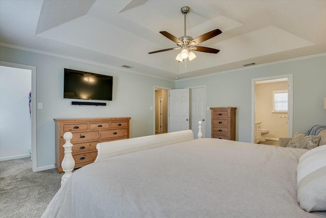 carpeted bedroom with baseboards, a raised ceiling, ornamental molding, and ensuite bathroom