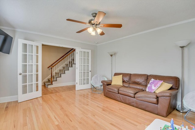 living area with stairway, ornamental molding, french doors, and wood finished floors