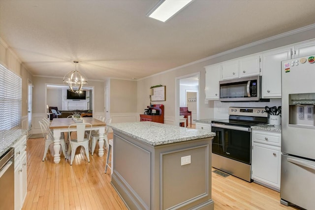 kitchen featuring light wood-style floors, a kitchen island, appliances with stainless steel finishes, and crown molding