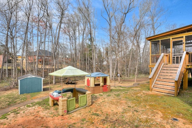 view of yard featuring stairs, an outbuilding, a shed, and a sunroom