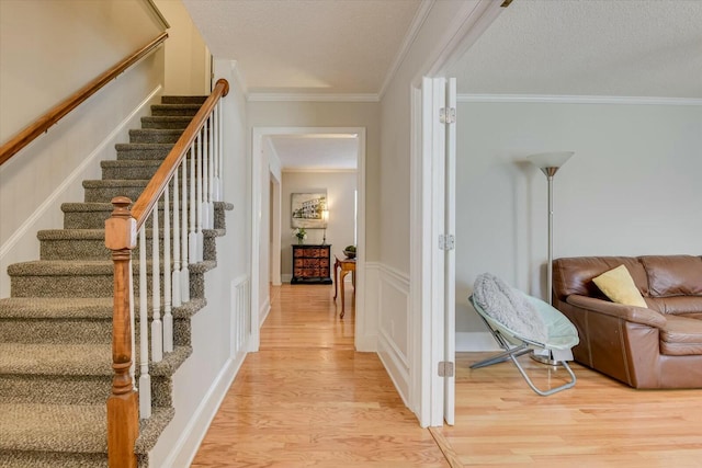 interior space with crown molding, stairway, light wood finished floors, and a textured ceiling