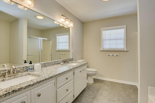 bathroom featuring double vanity, baseboards, a stall shower, and a sink