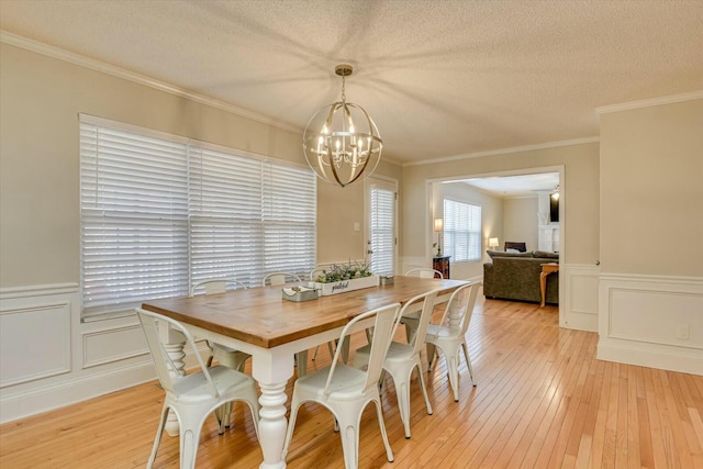 dining area with a chandelier, crown molding, a textured ceiling, and light wood-type flooring