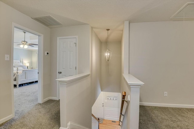 hallway featuring visible vents, an upstairs landing, carpet, and attic access