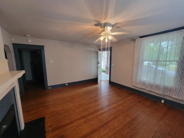 unfurnished living room featuring dark hardwood / wood-style flooring and ceiling fan