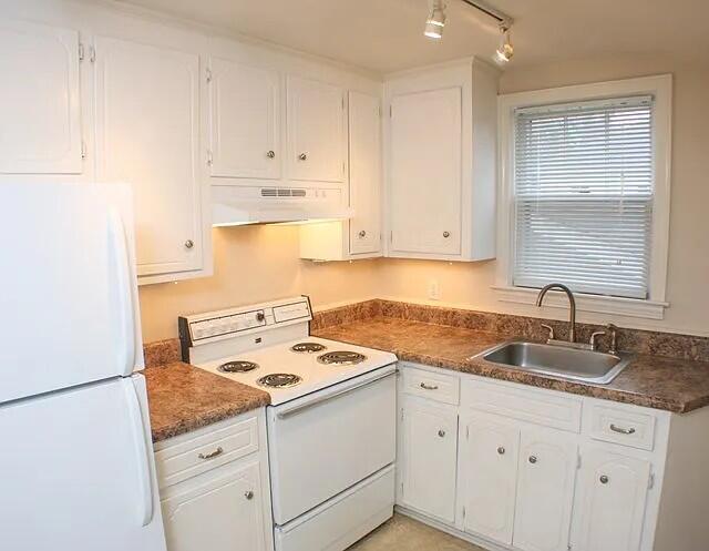 kitchen featuring white cabinetry, sink, track lighting, and white appliances