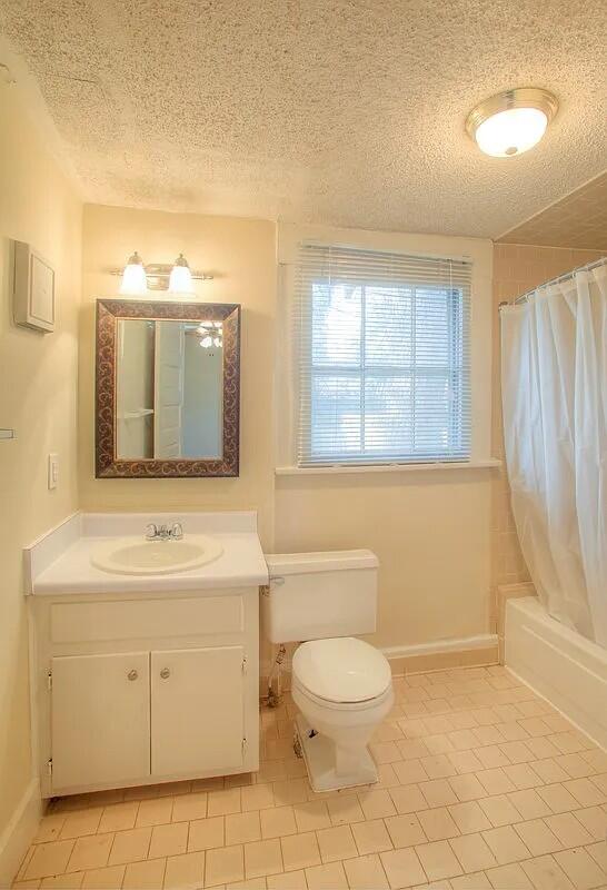 full bathroom with tile patterned floors, vanity, shower / tub combo, and toilet