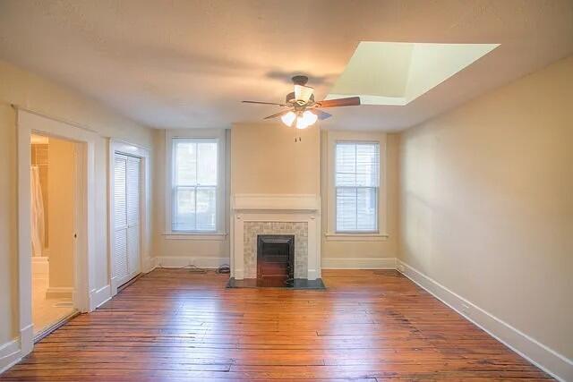 unfurnished living room with a fireplace, hardwood / wood-style flooring, and ceiling fan