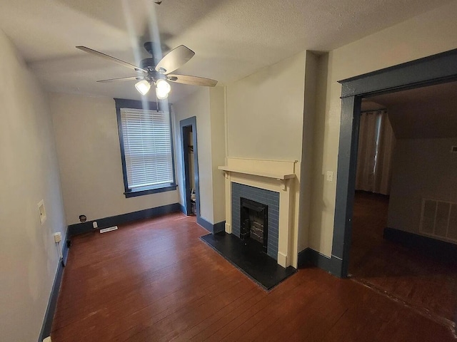 unfurnished living room featuring ceiling fan, dark hardwood / wood-style floors, and a textured ceiling