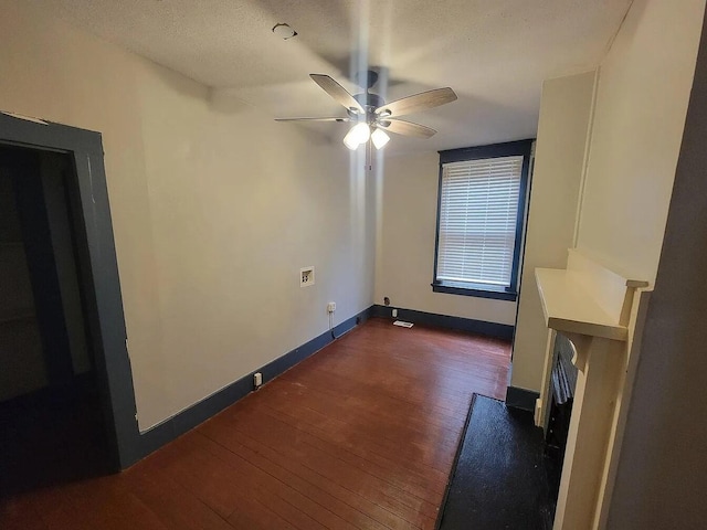 empty room with ceiling fan, dark hardwood / wood-style flooring, and a textured ceiling