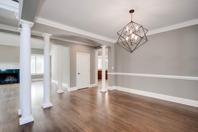unfurnished dining area featuring ornamental molding, baseboards, dark wood finished floors, arched walkways, and a fireplace