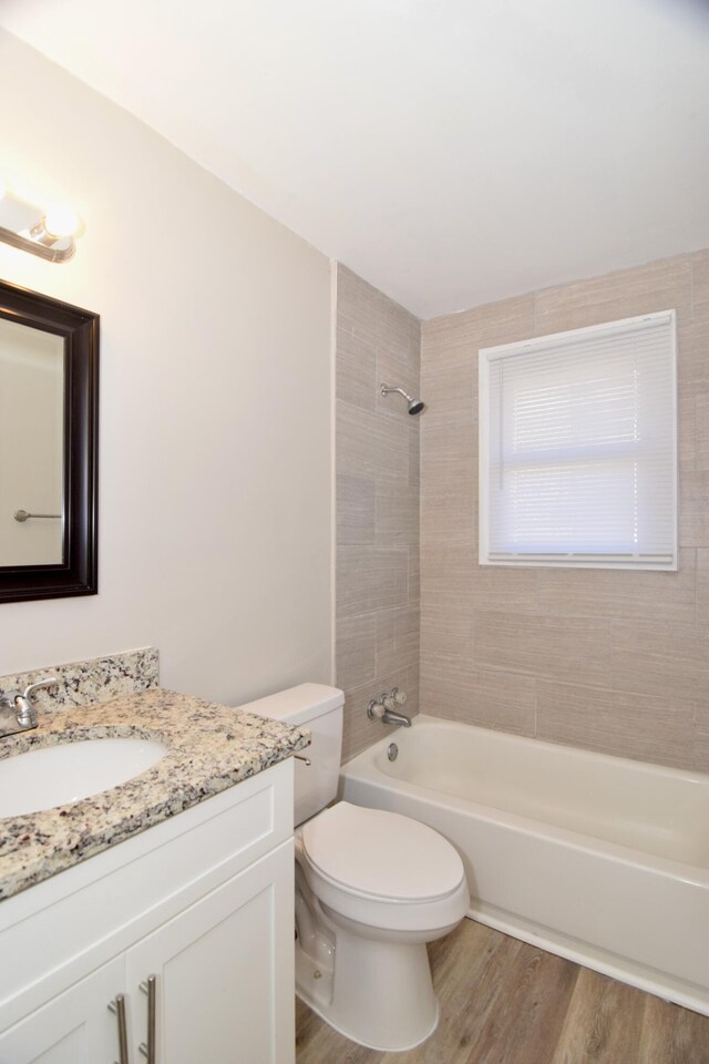 full bathroom with vanity, hardwood / wood-style flooring, toilet, and tiled shower / bath