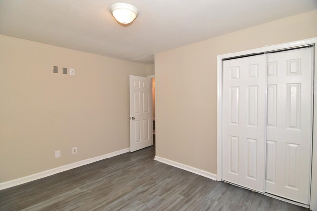 unfurnished bedroom with a closet and dark wood-type flooring