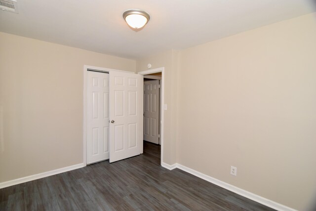 unfurnished bedroom with a closet and dark hardwood / wood-style flooring