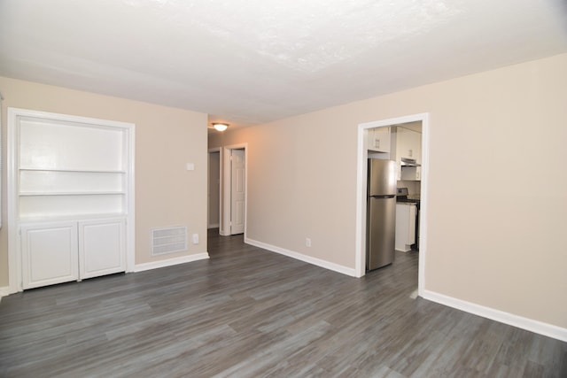 spare room featuring built in features and dark wood-type flooring