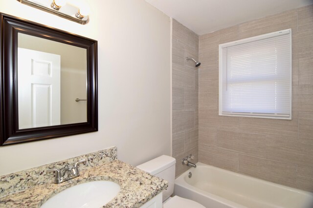 full bathroom with vanity, toilet, and tiled shower / bath combo