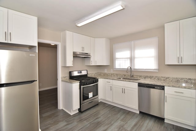 kitchen featuring light stone counters, stainless steel appliances, white cabinetry, and sink