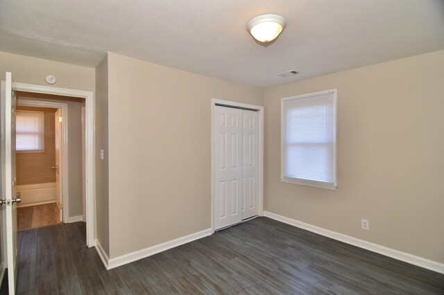 unfurnished bedroom featuring dark hardwood / wood-style flooring and a closet