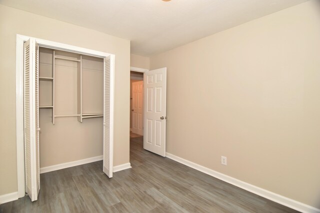 unfurnished bedroom with dark hardwood / wood-style flooring and a closet