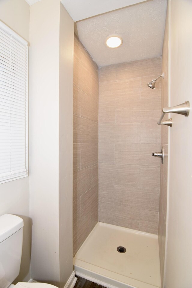 bathroom featuring a tile shower and toilet