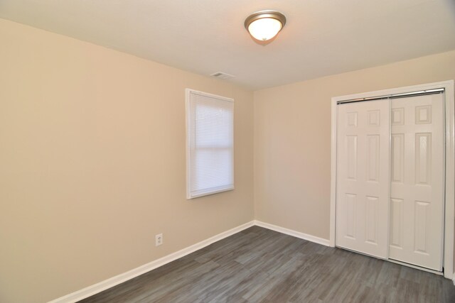 unfurnished bedroom with dark hardwood / wood-style floors and a closet