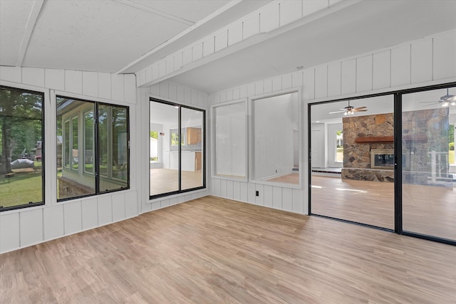 unfurnished sunroom featuring a fireplace and ceiling fan