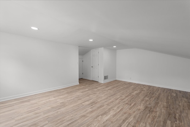 additional living space featuring lofted ceiling and light wood-type flooring