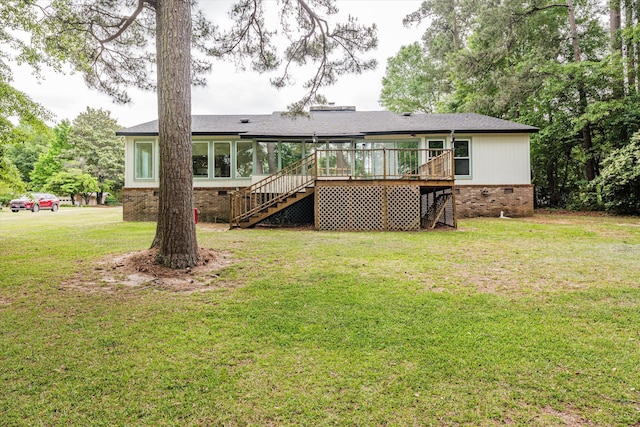 rear view of property featuring a lawn, a sunroom, and a wooden deck