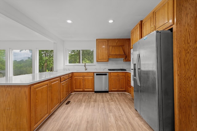 kitchen with kitchen peninsula, stainless steel appliances, a healthy amount of sunlight, and sink