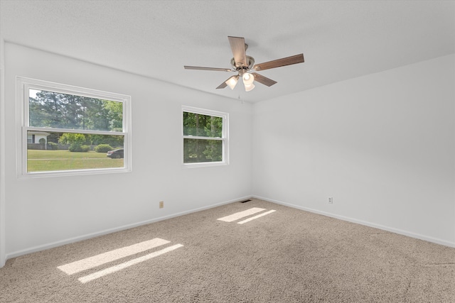 carpeted spare room with ceiling fan and plenty of natural light