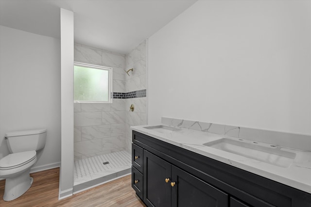 bathroom featuring a tile shower, vanity, toilet, and wood-type flooring