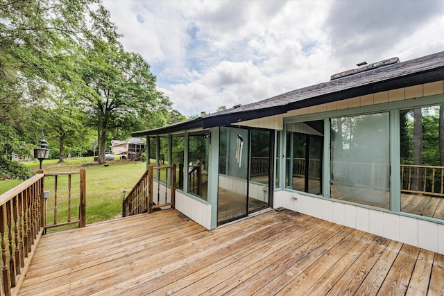 wooden terrace featuring a lawn and a sunroom