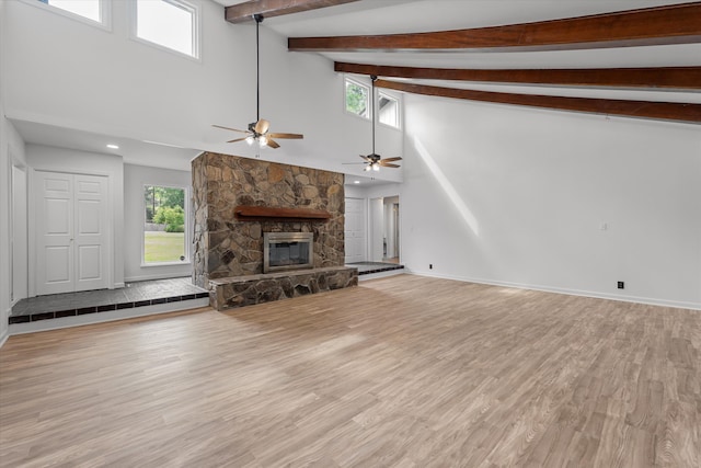 unfurnished living room with beam ceiling, ceiling fan, high vaulted ceiling, a fireplace, and light wood-type flooring