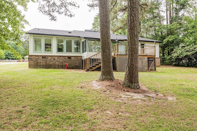 rear view of house with a sunroom, a yard, and a wooden deck