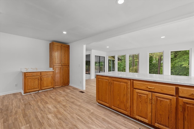 kitchen featuring kitchen peninsula, light stone counters, and light hardwood / wood-style flooring