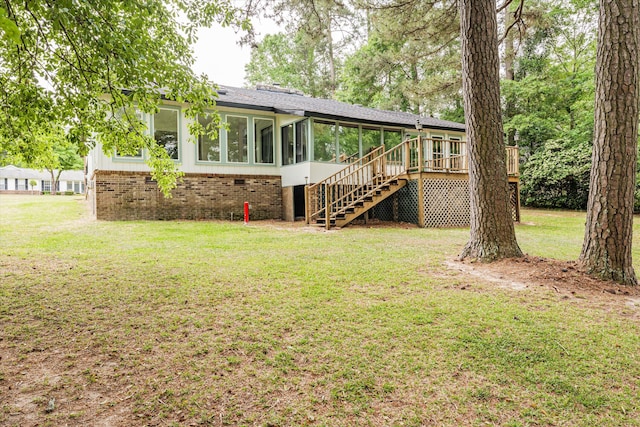 rear view of house with a wooden deck, a sunroom, and a yard