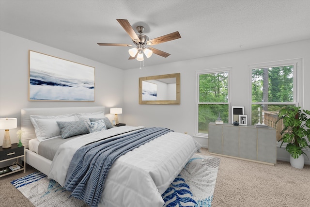 bedroom with carpet flooring, ceiling fan, a textured ceiling, and multiple windows