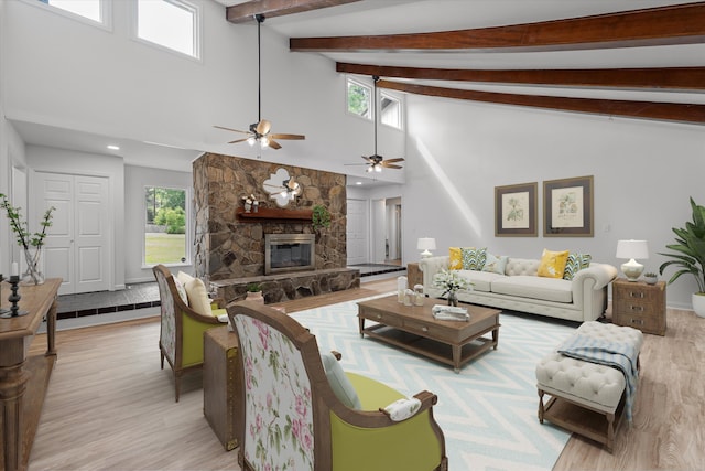 living room featuring ceiling fan, lofted ceiling with beams, light hardwood / wood-style floors, and a fireplace