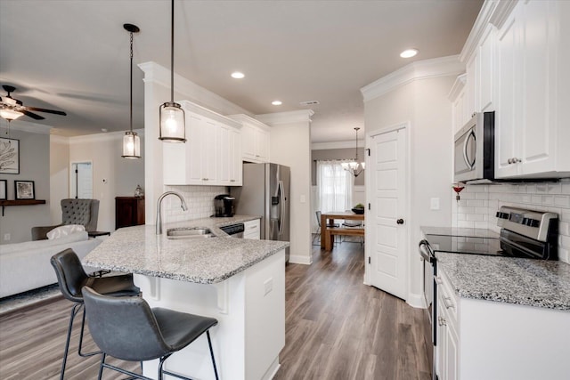 kitchen with light stone countertops, stainless steel appliances, sink, pendant lighting, and white cabinets