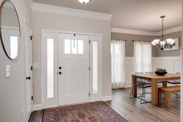 foyer with hardwood / wood-style floors, a notable chandelier, and ornamental molding