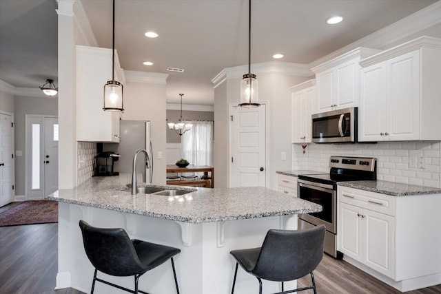 kitchen with white cabinetry, sink, stainless steel appliances, light stone counters, and kitchen peninsula