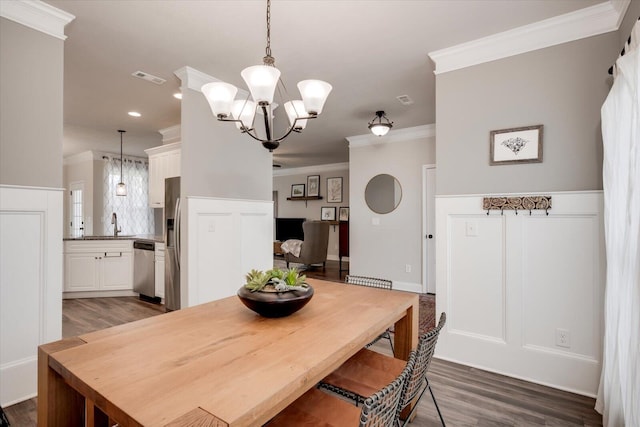 dining space with dark hardwood / wood-style flooring, a notable chandelier, ornamental molding, and sink