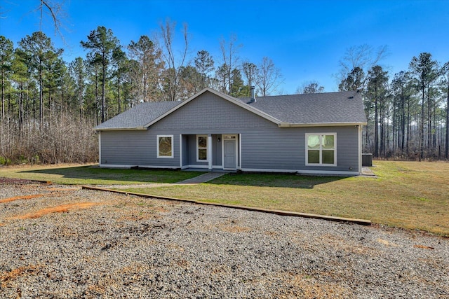 view of front of property with central air condition unit, a shingled roof, and a front yard